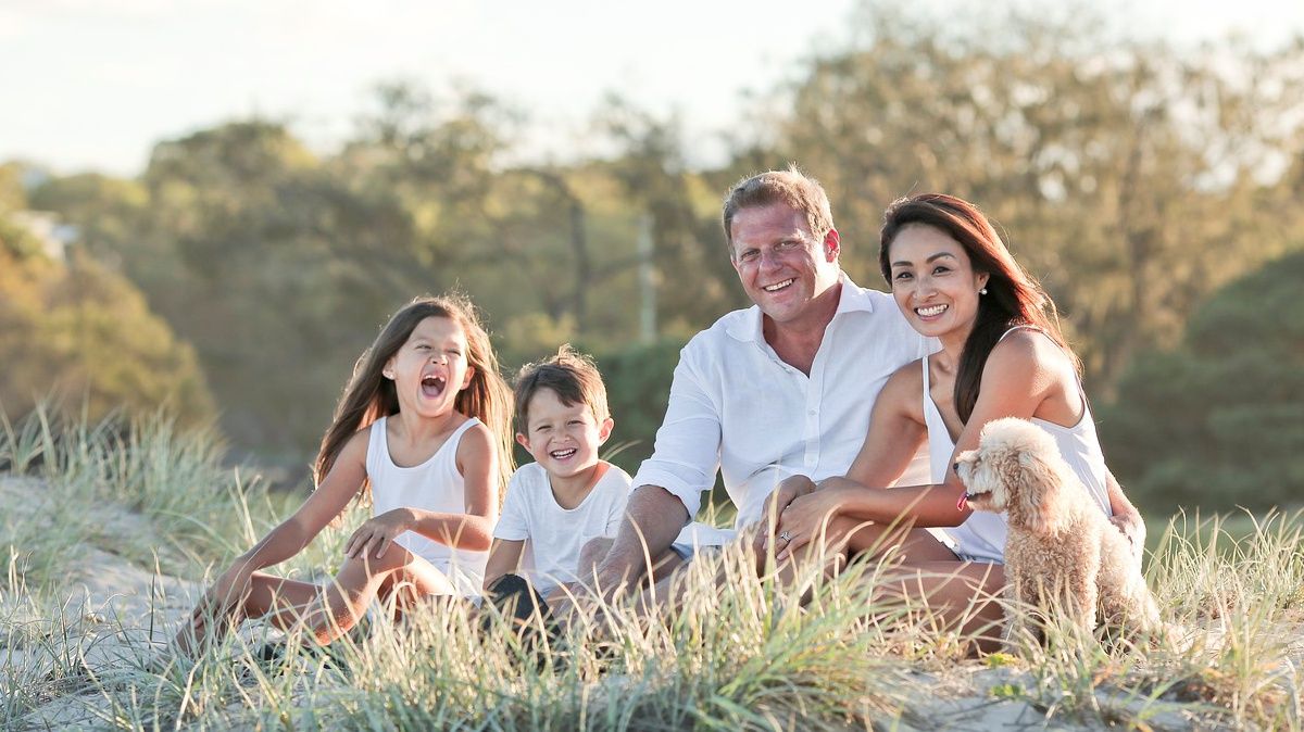 Na trawie siedzi rodzina, dwie osoby dorosłe i dwoje dzieci