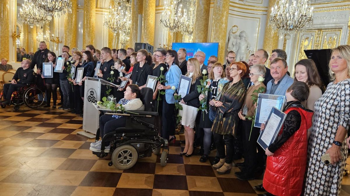 Kilkadziesiąt nagrodzonych osób stoi w półkolu - zdjęcie zrobione z boku