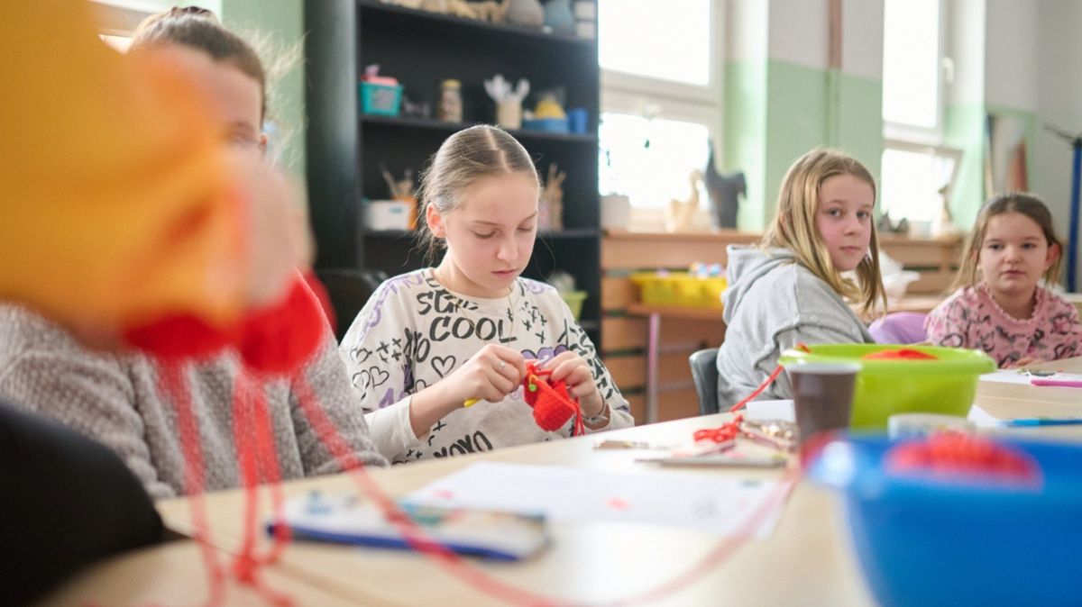 Cztery dziewczynki siedzą, podczas szydełkowania, przy stole