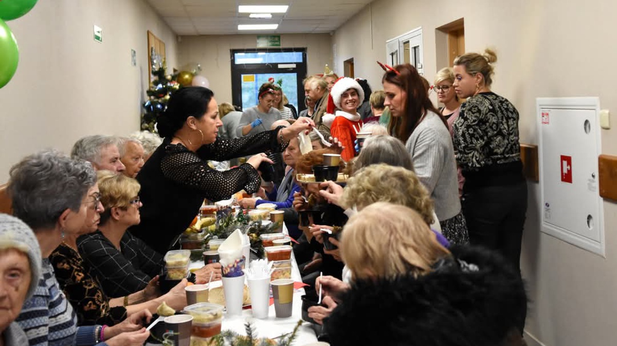 Grupa osób, jedni siedzą przy stole, inni stoją