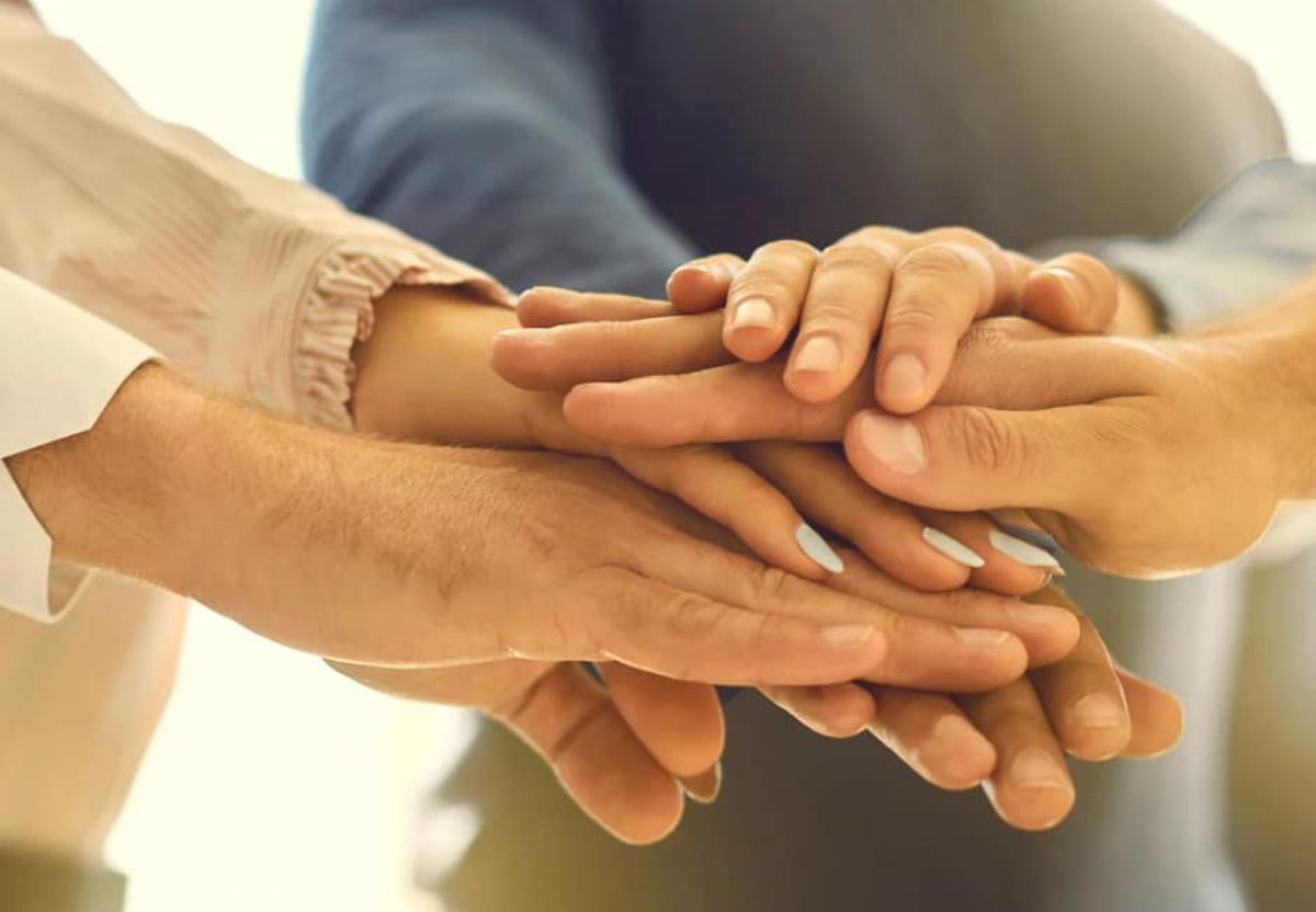 Ręce kilku osób ułożone jedna na drugiej