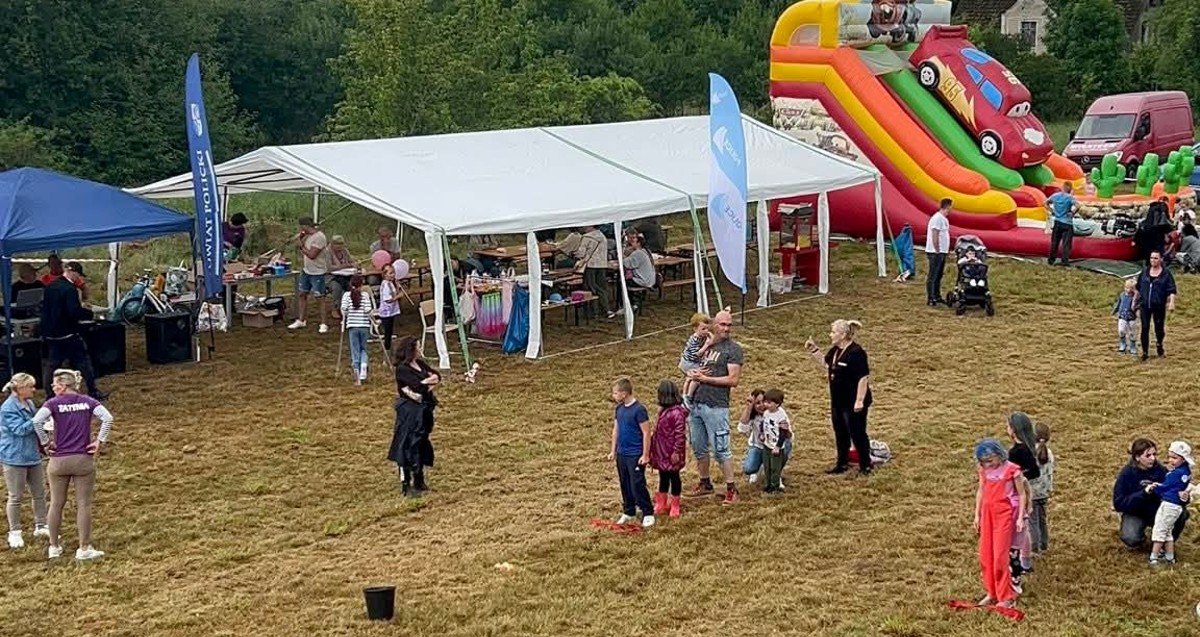 Zdjęcie festynowe - ludzie, w tle namioty, zjeżdżalnia