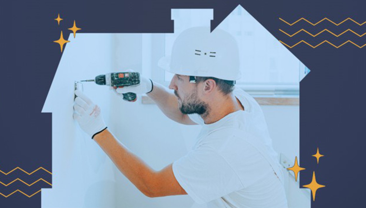 Mężczyzna w kasku i z wiertarką w ręku na tle białej makiety domu