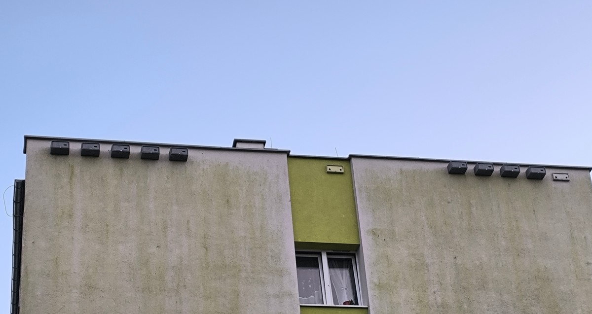 Kawałek ściany budynku z przymocowanymi budkami dla jerzyków