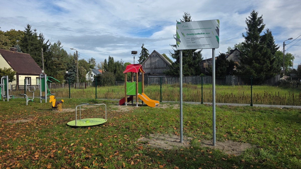 Widok na plac zabaw, na pierwszym planie tablica z napisem Granty Sołeckie i logami