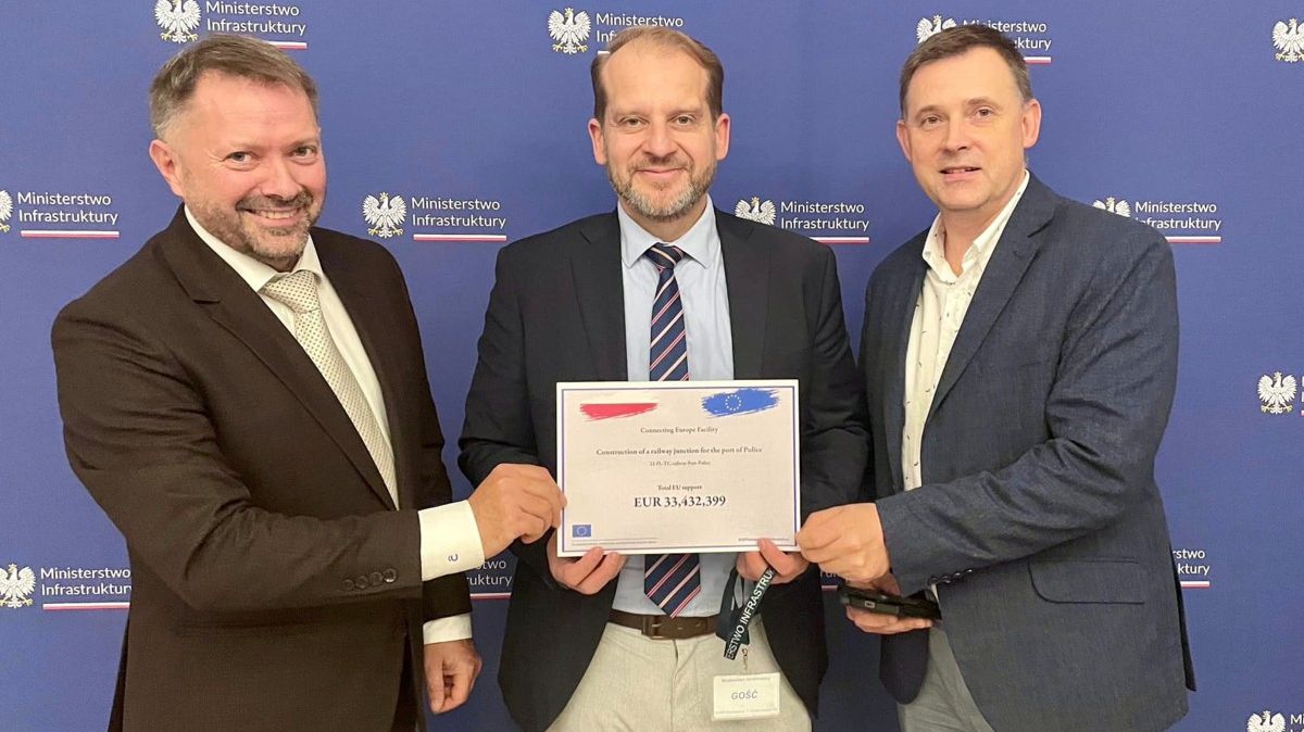 Trzey osoby stoją i trzymają tabliczkę z dofinansowaniem