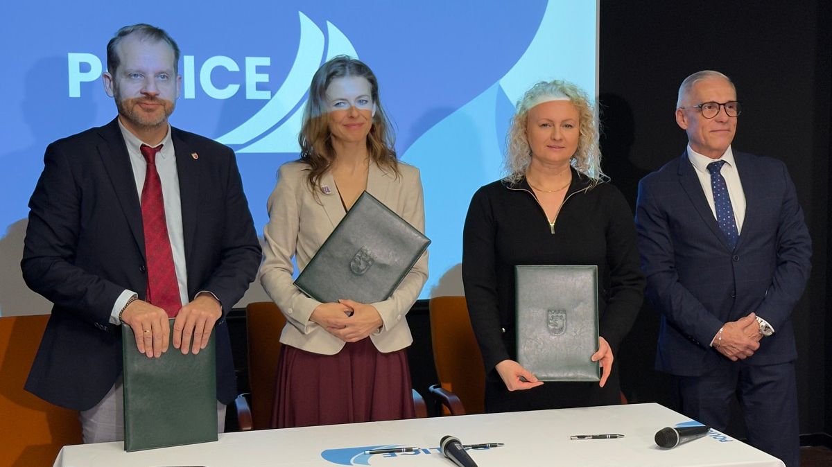 Cztery osoby, które podpisały porozumienie, stoją trzymając w rękach teczki z dokumentami