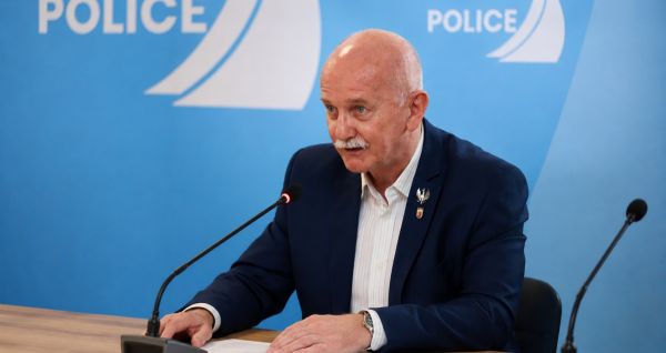 Na zdjęciu radny Wojciech Dudek, siedzi przy stole, na którym stoi mikrofon