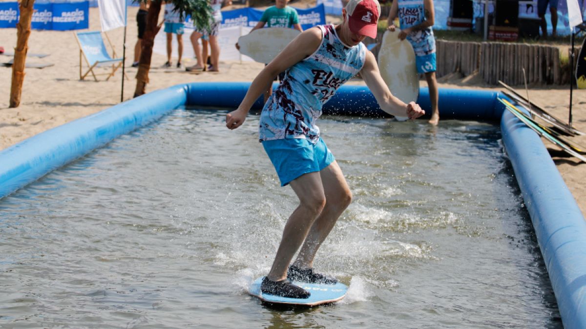 Flowup - młody chłopak na desce w basenie rozstawionym na plaży