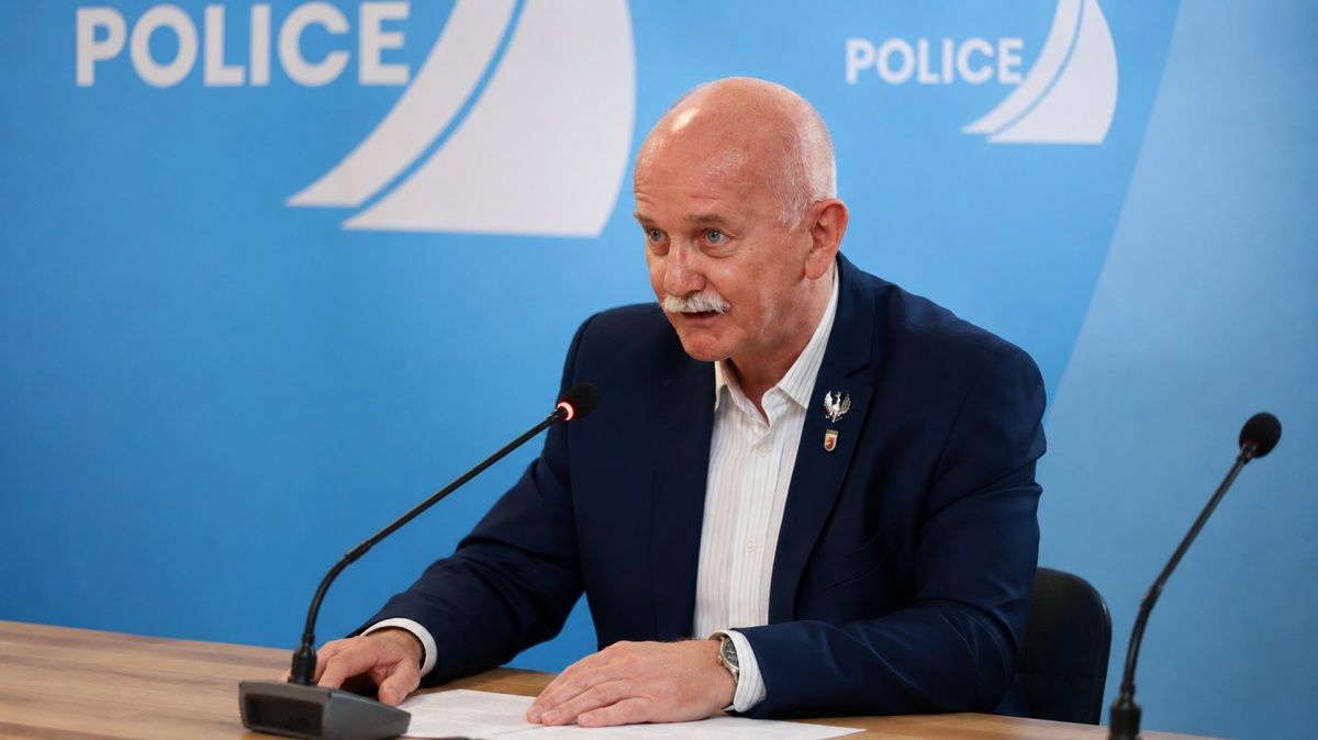 Na zdjęciu radny Wojciech Dudek, siedzi przy stole, na którym stoi mikrofon