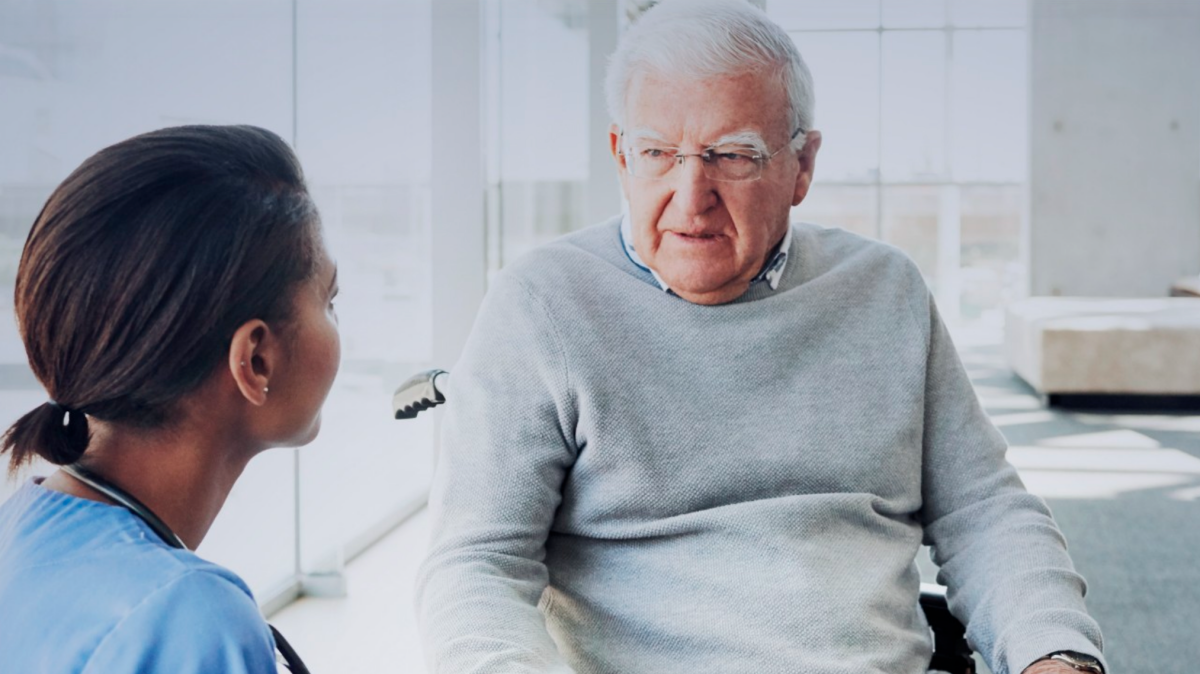 Dwie osoby siedzą. Tyłem siedzi kobieta-lekarz, przodem starszy mężczyzna