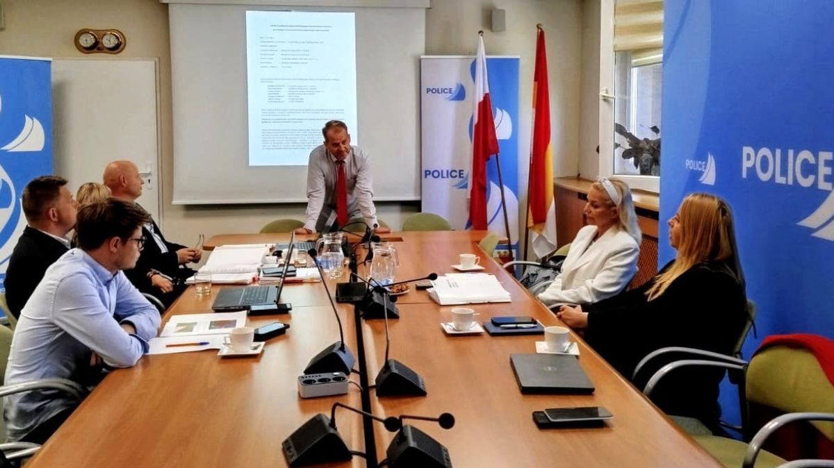 Spotkanie kilka osób siedzi przy stole, jedna osoba stoi oparta o stół