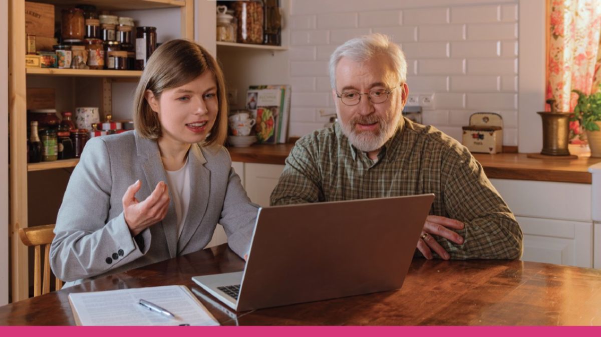 dwie osoby siedzą przy stole na  którym stoi laptop