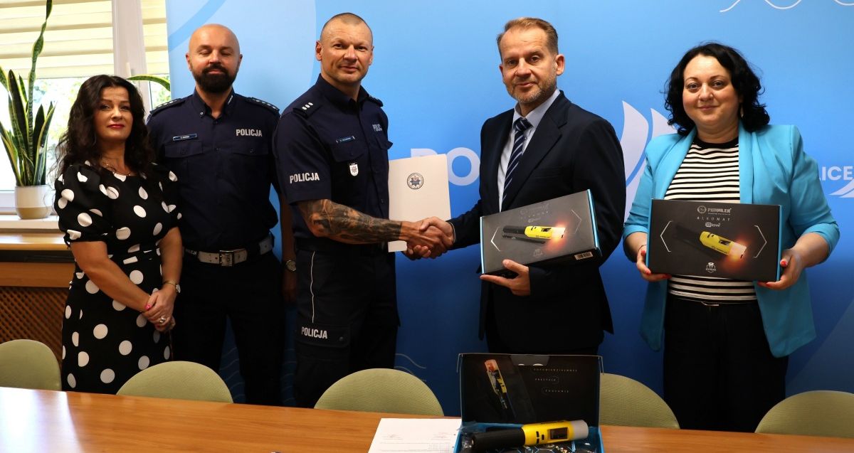 Przekazanie alkomatów - pięć osób stoi, dwie osoby podają sobie ręce