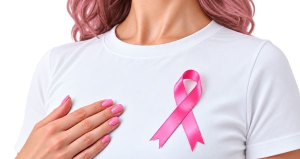 Kobieta w białej bluzce, do której przypięta jest różowa wstążeczka