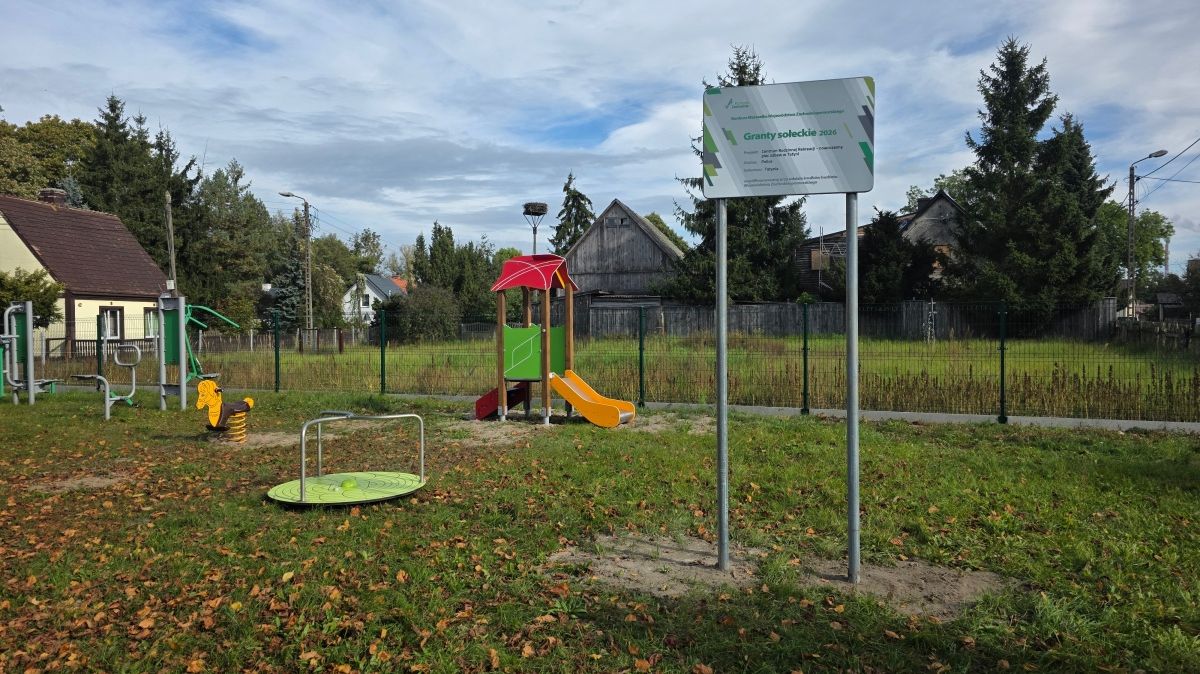 Widok na plac zabaw, na pierwszym planie tablica z napisem Granty Sołeckie i logami