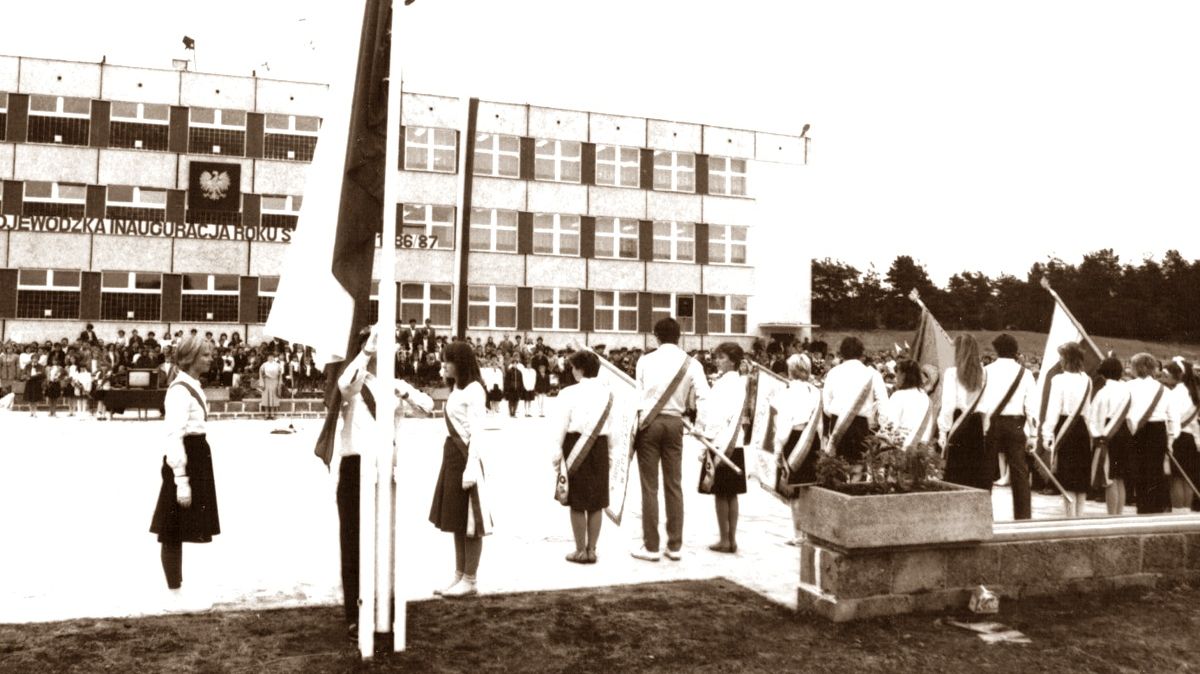 Wojewódzka inauguracja nowego roku szkolnego 1986/1987 w SP nr 8. na pierwszym planie tyłem odwrócone poczty sztandarowe w tle budynek szkoły