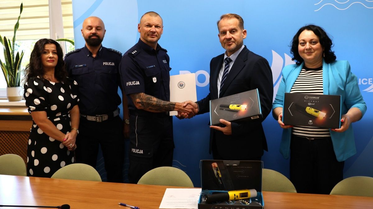 Przekazanie alkomatów - pięć osób stoi, dwie osoby podają sobie ręce