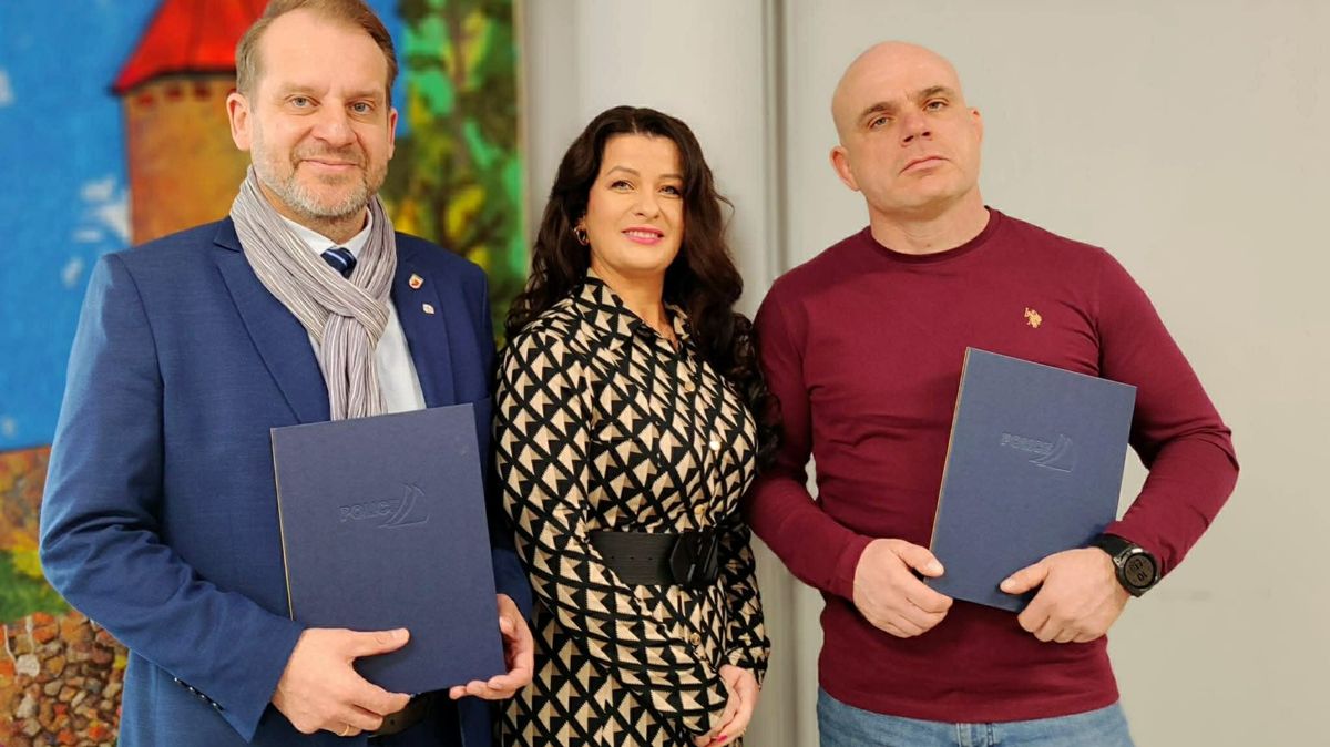 Trzy osoby na zdjęciu. Dwóch mężczyzn i pośrodku kobieta. Mężczyźni trzymają w rękach granatowe teczki.