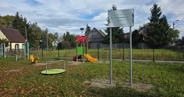 Widok na plac zabaw, na pierwszym planie tablica z napisem Granty Sołeckie i logami