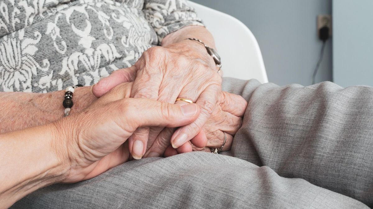 osoba trzymającą starszą osobę za rękę