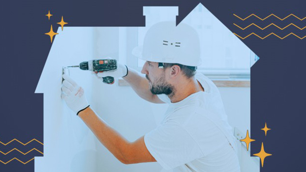 Mężczyzna w kasku i z wiertarką w ręku na tle białej makiety domu