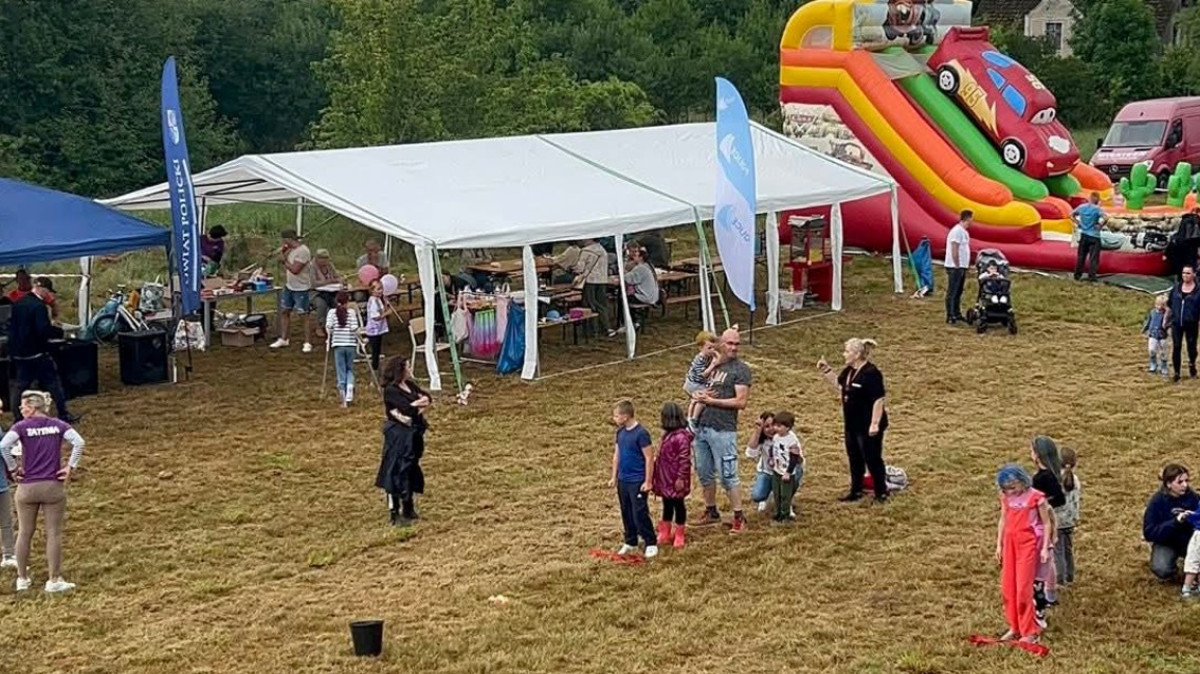 Zdjęcie festynowe - ludzie, w tle namioty, zjeżdżalnia