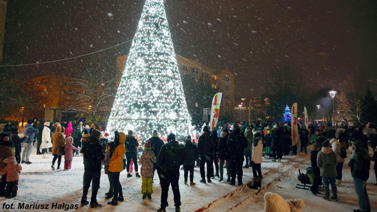 Plac, na środku świecąca choinka sztuczna, wokół ludzie