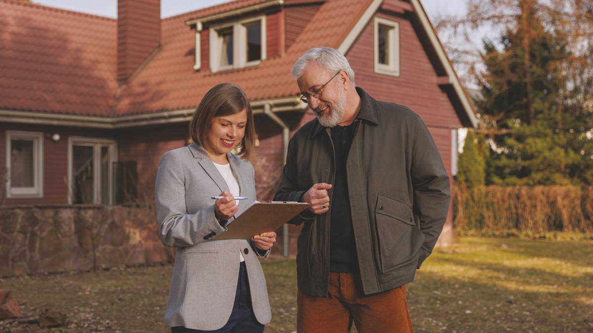 Kobieta i mężczyzna stoją przed domem i patrzą na dokumenty