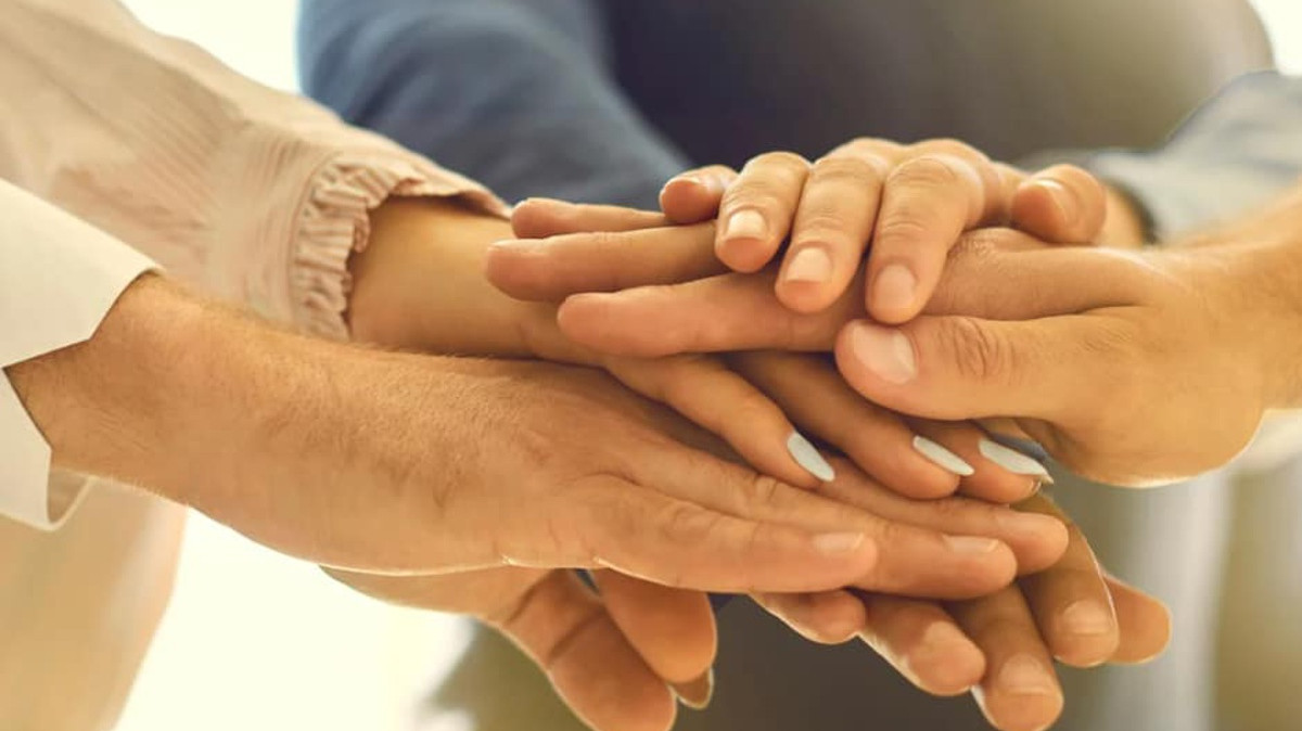 Ręce kilku osób ułożone jedna na drugiej