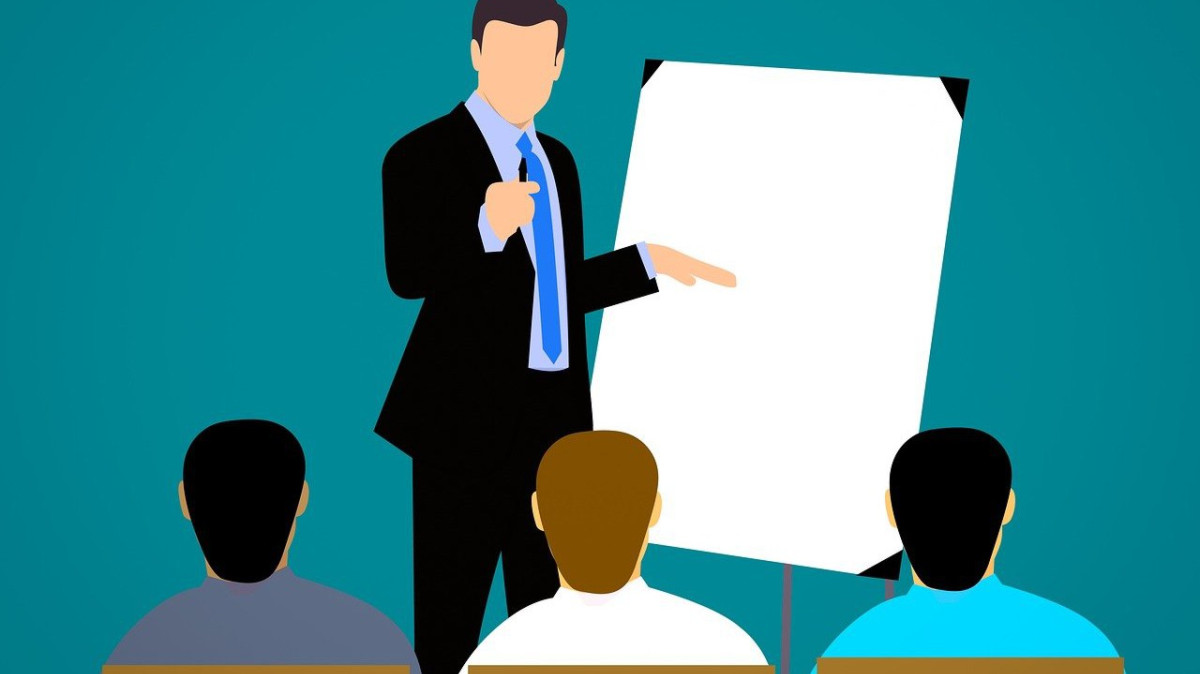 grafika, jedna osoba stoi przy tablicy, trzy siedzą tyłem