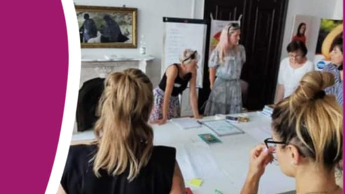 zdjęcie z plakatu - osoby siedzące, stojące wokół stołu