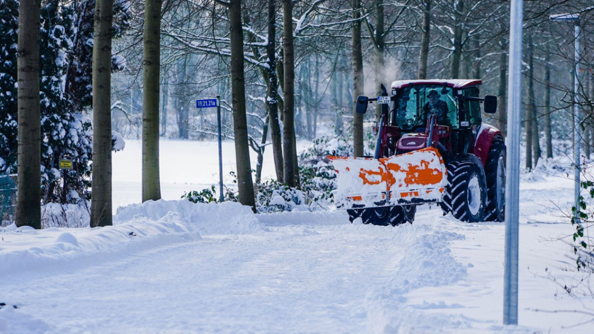 Traktor z pługiem odśnieża ulicę