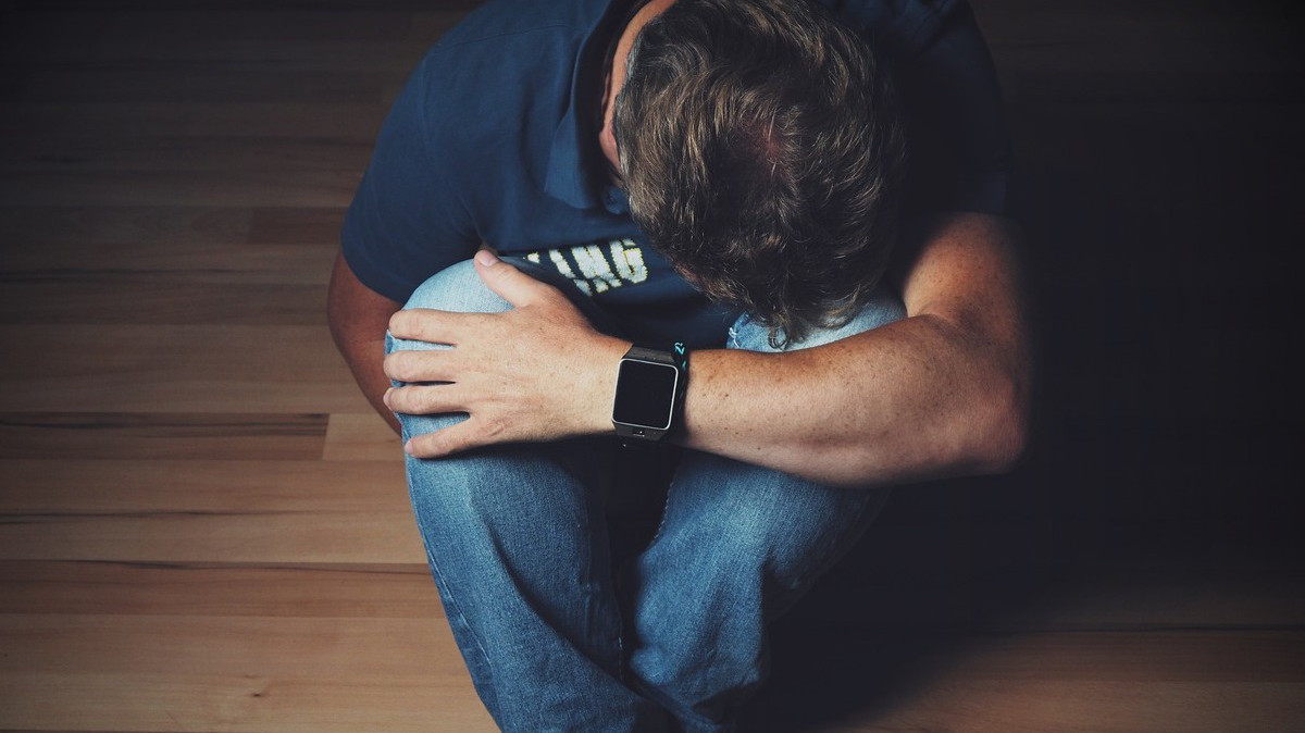 skulony mężczyzna siedzący na podłodze