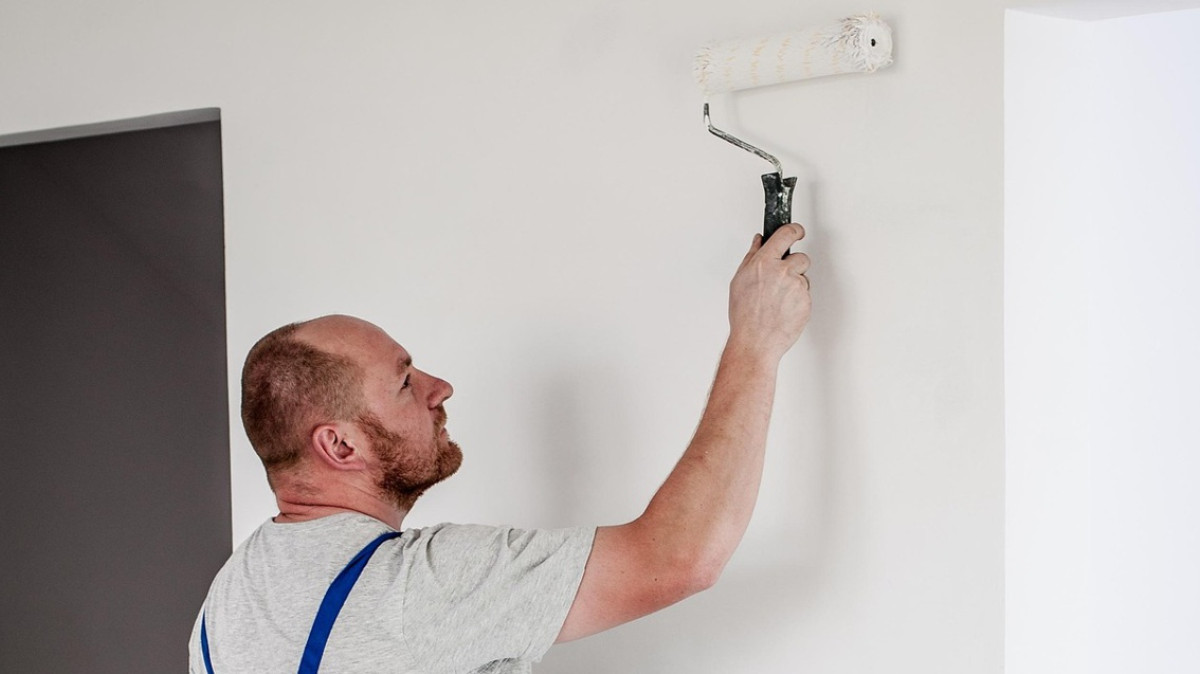 mężczyzna maluje ścianę wałkiem