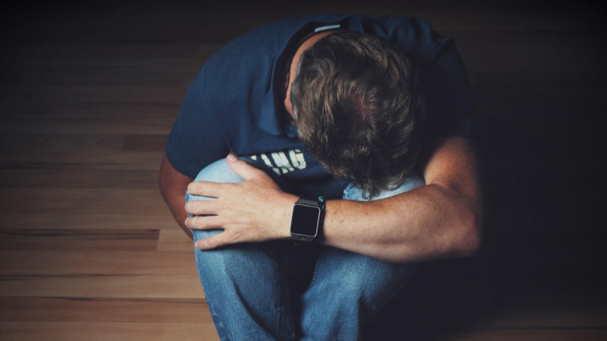 Skulony mężczyzna siedzi na podłodze