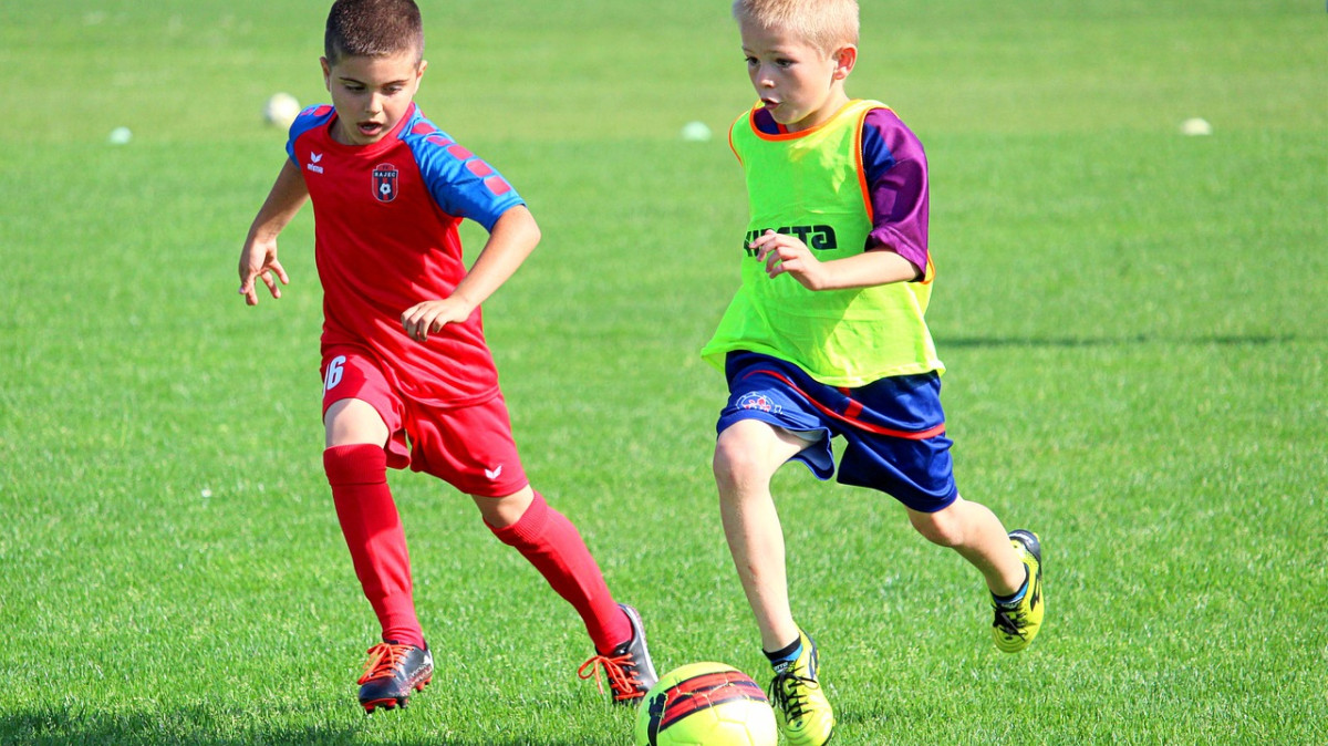 Dwóch chłopców biegnie za piłką