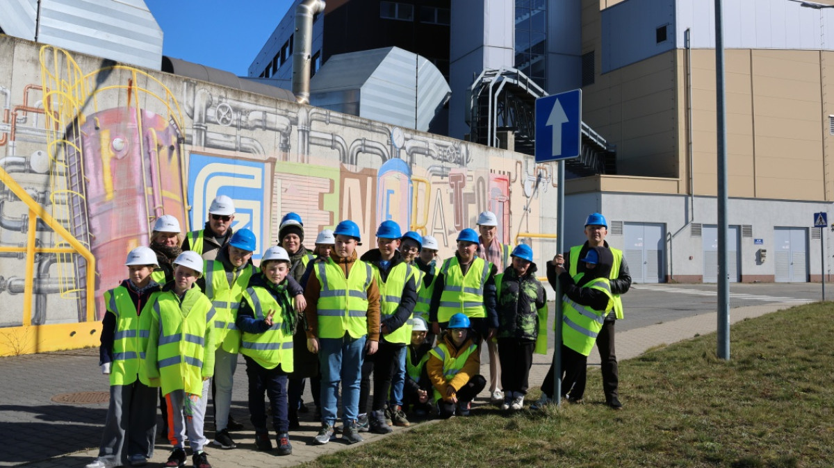 Na zdjęciu grupa dzieci wraz opiekunami przed budynkiem EcoGeneratora