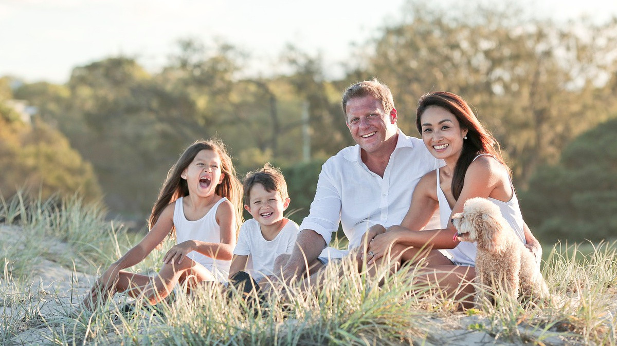 Na trawie siedzi rodzina, dwie osoby dorosłe i dwoje dzieci